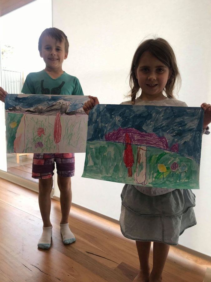 Two children holding up the paintings they made